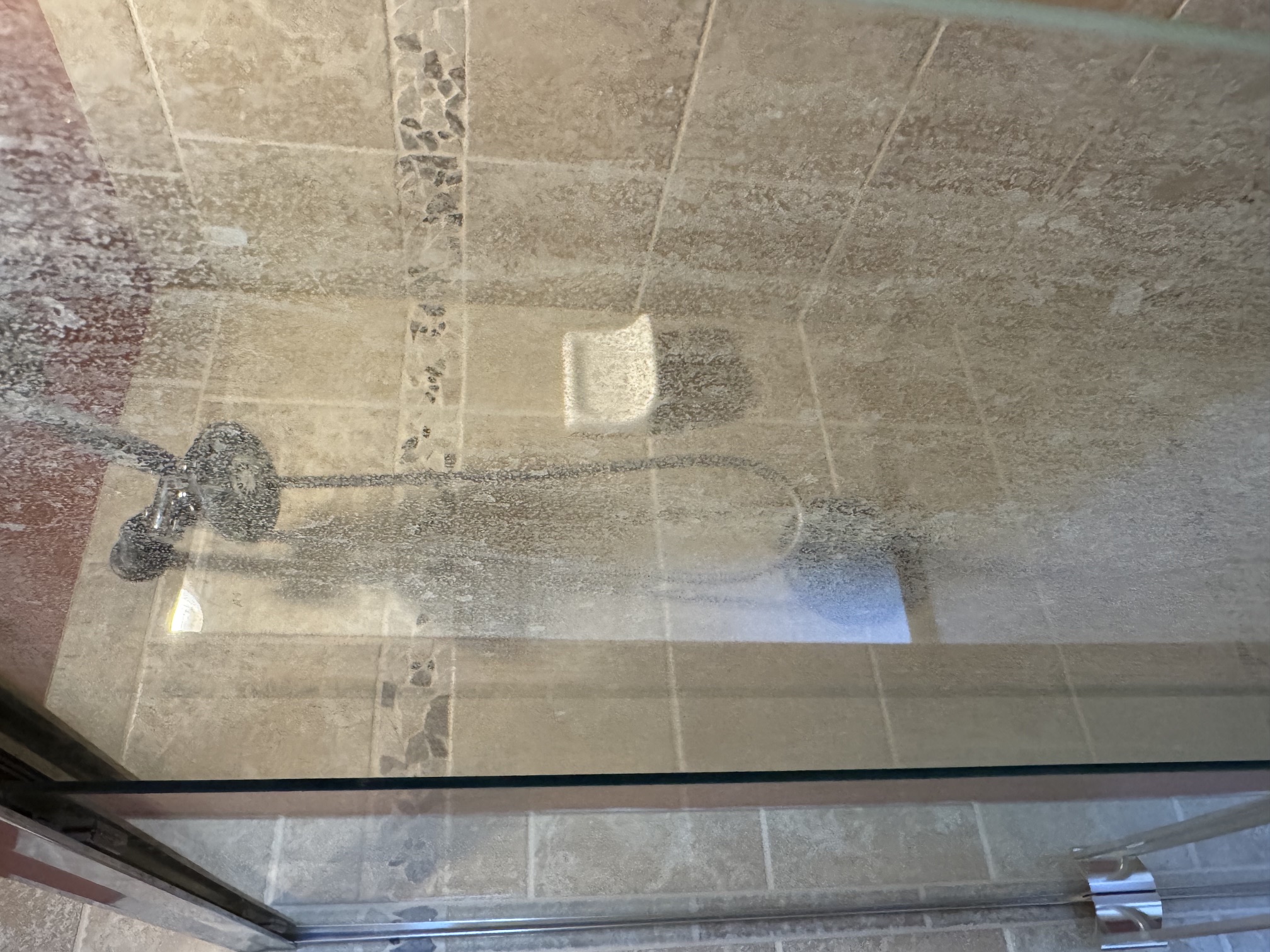Hazy glass shower door covered in hard water and soap scum before cleaning